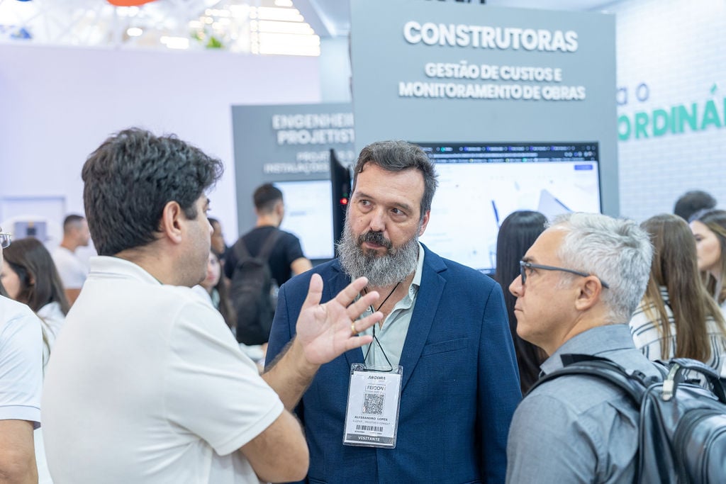 homens conversando no estande da altoqi atras um painel está escrito construtoras, gestão de custos e monitoramento de obras