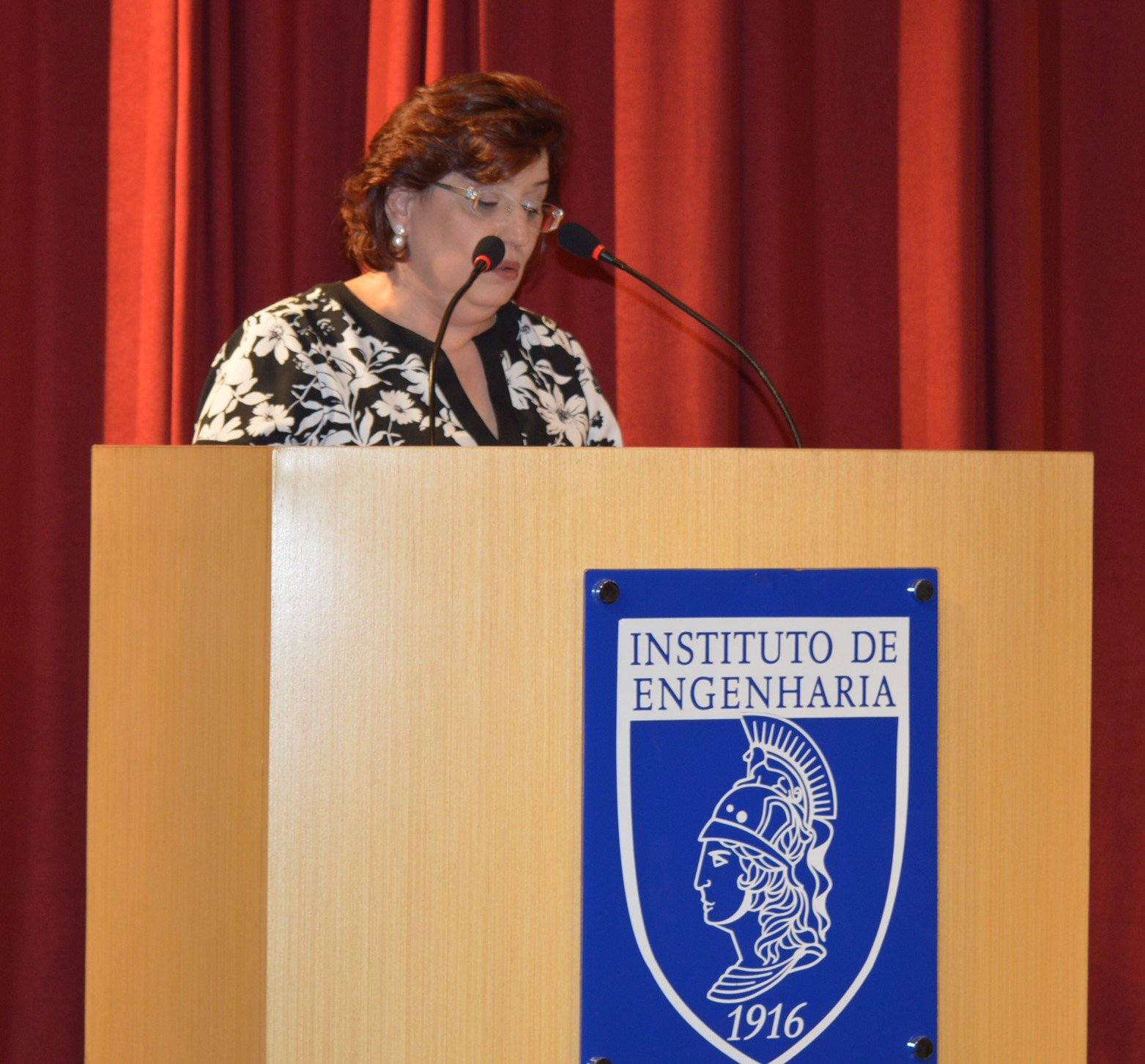 Mulher no palco palestrando com dois microfones sobre ser engenheira do ano
